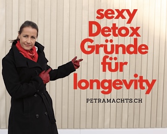 Petra steht vor Hausfassade in Bretteroptik und zeigt auf die rote Schrift, die sagt: Detox for longevity